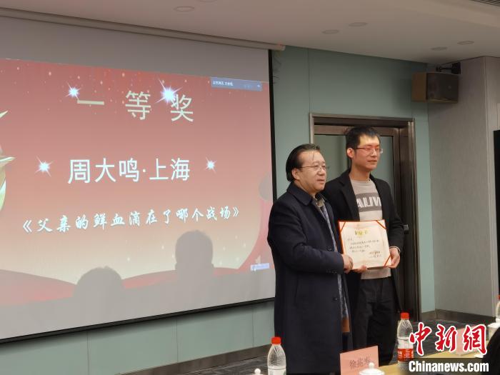 圖為作家、西北師范大學(xué)新聞與傳媒學(xué)院院長徐兆壽頒發(fā)一等獎證書，代領(lǐng)獎?wù)呱吓_領(lǐng)獎?！钅?攝