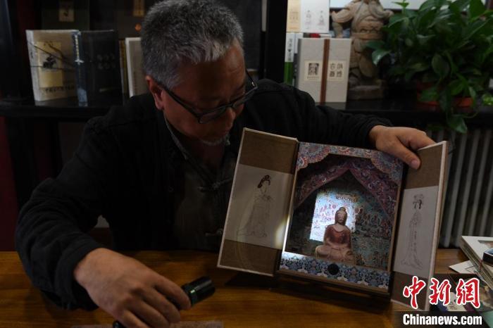 圖為讀者出版集團(tuán)讀者晉林工作室獨(dú)立出品人徐晉林，展示互動(dòng)性強(qiáng)的敦煌題材手工書。(資料圖) 楊艷敏 攝