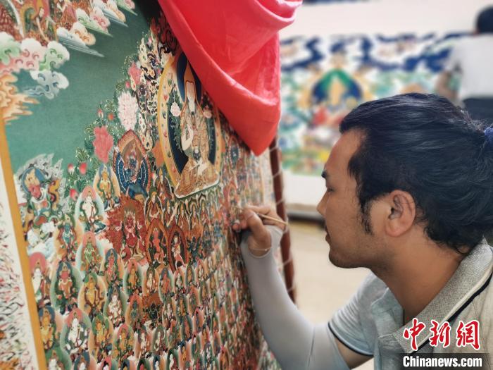 圖為更登才讓的徒弟繪畫(huà)唐卡?！?zhí)砀?攝