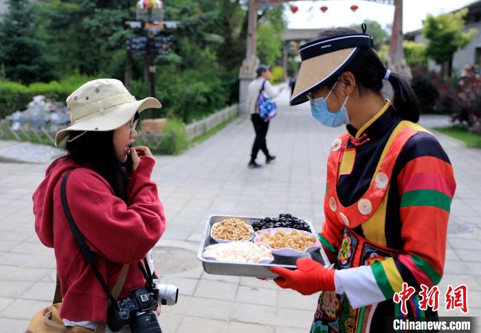 圖為身穿土族服飾的女性介紹當(dāng)?shù)靥厣〕?。　薛?攝