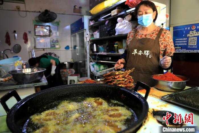 圖為平安驛·河湟民俗文化體驗(yàn)地內(nèi)的商戶炸干板魚(yú)。　薛蒂 攝