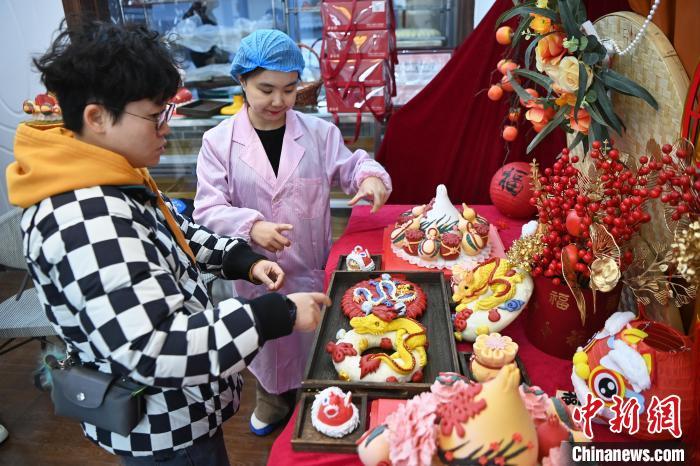 1月25日，隨著春節(jié)臨近，蘭州一花饃店“龍”元素花饃熱銷。圖為工作人員向顧客推薦“龍”元素花饃。九美旦增 攝</p><p>