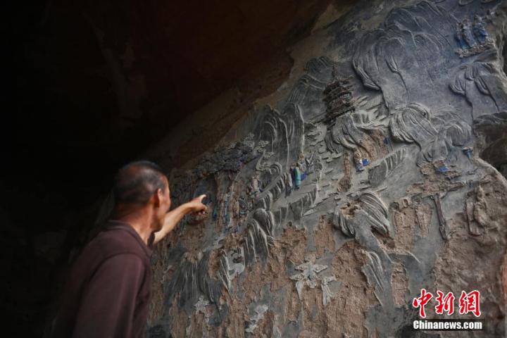 7月15日，甘肅省平?jīng)鍪袥艽h百里石窟長廊羅漢洞石窟內(nèi)，該窟文保員郭建平介紹窟內(nèi)石刻彩繪壁畫。郭建平家中三代人曾自發(fā)保護羅漢洞石窟。羅漢洞石窟遺存40余個窟龕，以北魏至清代風格為主。中新社記者 李亞龍 攝