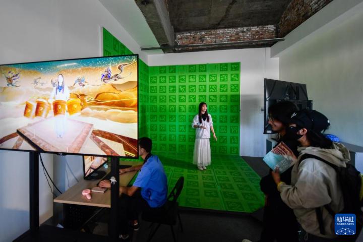 7月22日，游客體驗(yàn)“尋境敦煌——數(shù)字敦煌沉浸展”后，在虛擬演播廳拍攝一段真人與洞窟虛擬場景交互的視頻。新華社記者 郎兵兵 攝</p>
<p>